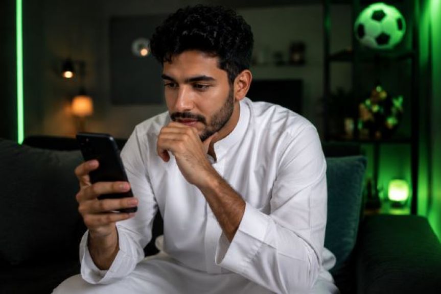 رجل يتابع أسعار مراهنات كرة القدم عبر الهاتف داخل المنزل 